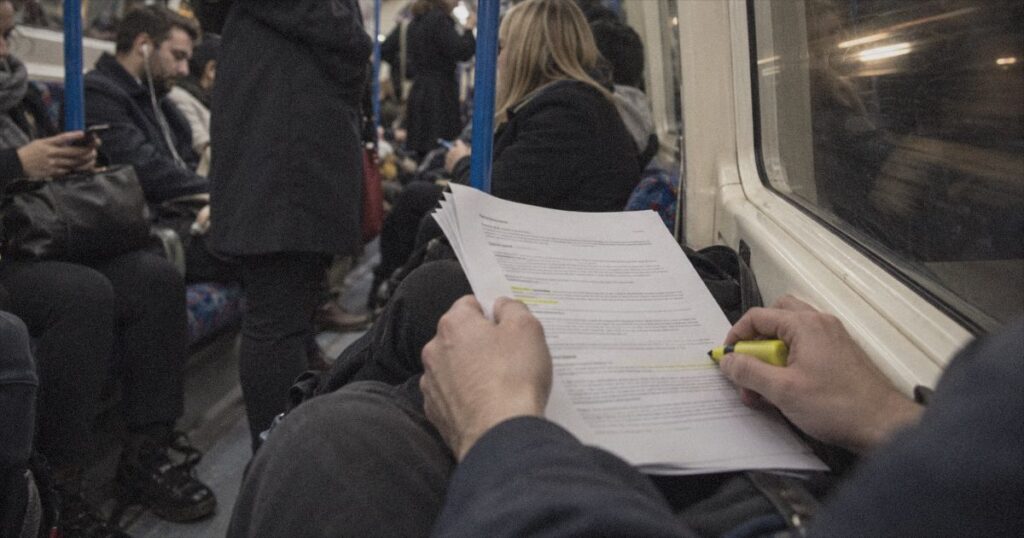 Skilled Worker salary threshold 2026: a graduate reading a UK job offer on the Tube